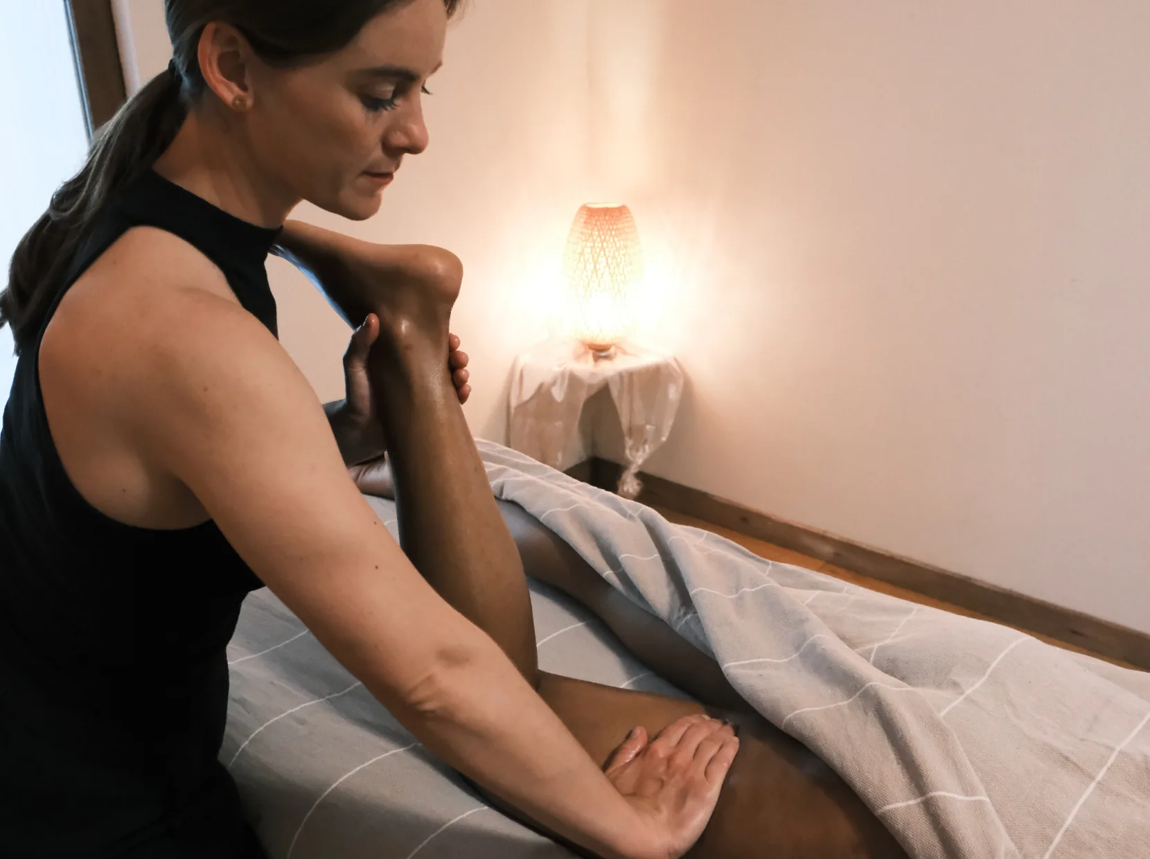Camille pendant un massage à l'huile, la jambe pliée soutenue à deux mains